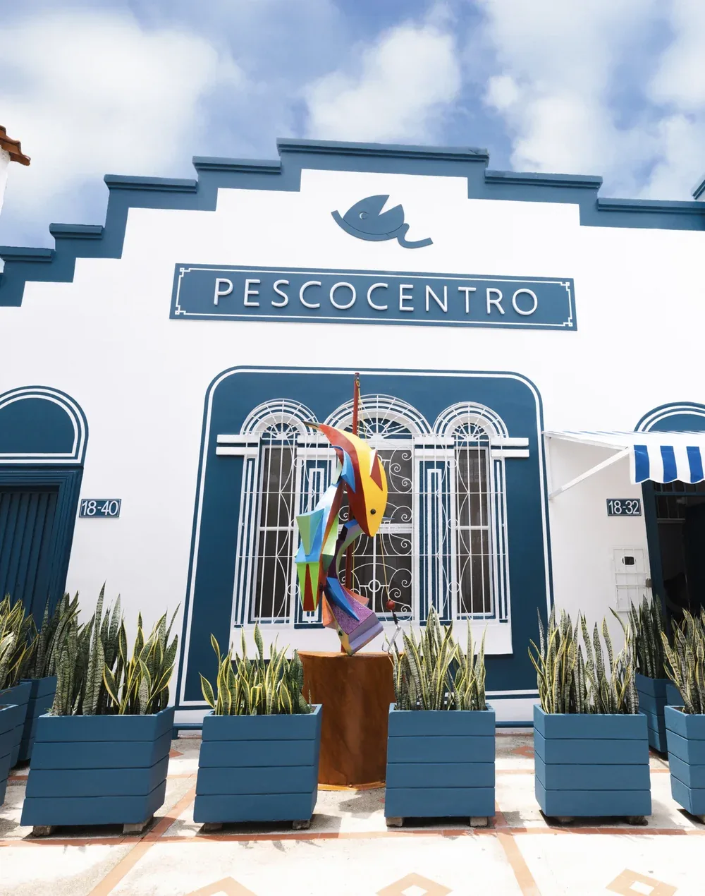 Fachada azul y blanca de Pescocentro Búcaro con escultura de pez, Calle 21 en Bucaramanga