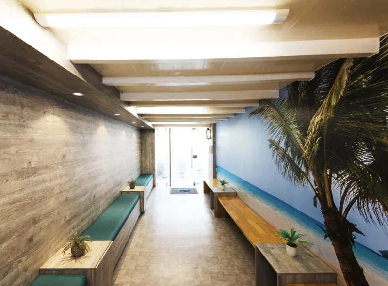 Pasillo de entrada con bancas y mural de playa con palmera en Pescocentro Búcaro, Bucaramanga